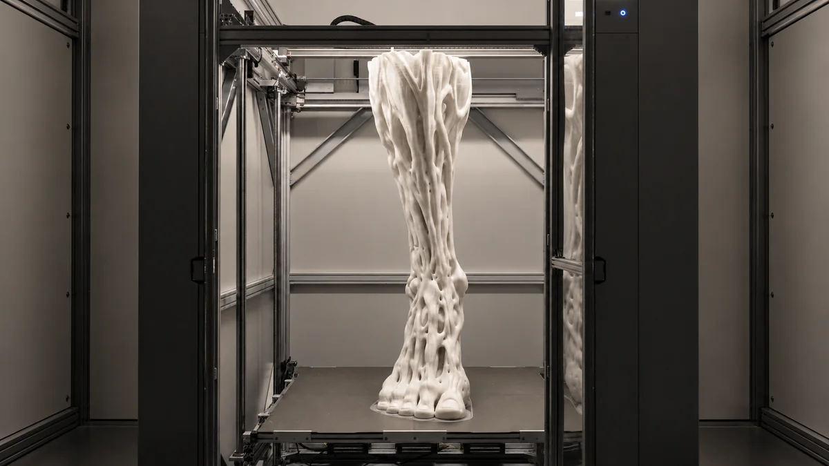 Full view of the pale sculptural form inside its fabrication enclosure.